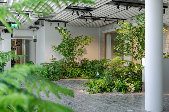 In die gebaute Struktur eingeschriebene Miniaturlandschaft. „The Green Lane“ verbindet Zonen, rhythmisiert Wege, schafft Rückzugsorte und weiche Raumkanten.