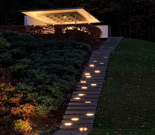 Der f�r Familienfeste konzipierte Gartenpavillon wird blendfrei durch LED-Lichtleisten auf der Mauerkrone beleuchtet. Die helle Deckenuntersicht dient als Reflexionsfl�che. Die Treppe wird durch unregelm��ig angeordnete LED-Linearbeleuchtungen beleuchtet, die in einen Falz der Stufen verdeckt eingelassen sind und dadurch nicht blenden.