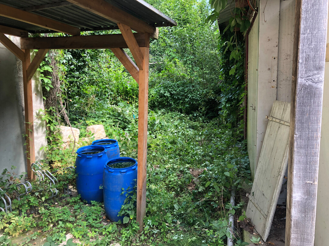 Schmaler Durchgang zwischen Wohnhaus, Fahrradunterstand und Container