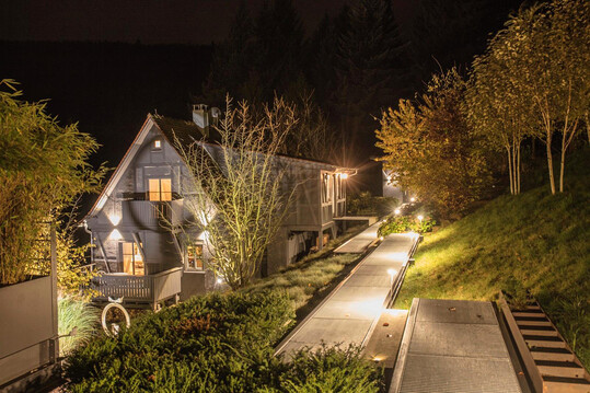 Metallstege verbinden eine moderne Villa mit einem historischen kleinen G�stehaus und einem Saunaanbau. Damit der Steg auch bei Dunkelheit angenehm und sicher zu begehen ist, wurden nur nach unten leuchtende Pollerleuchten entlang des Weges eingesetzt.