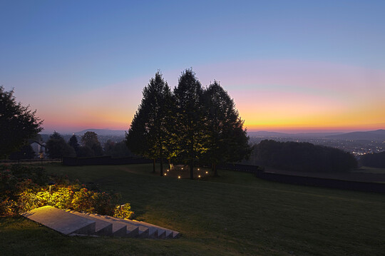 Ein am tiefsten Punkt dieses großen Privatgartens gelegenes Baumrondell mit sieben Kaiserlinden wird durch Bodeneinbaustrahler sehr zurückhaltend akzentuiert.