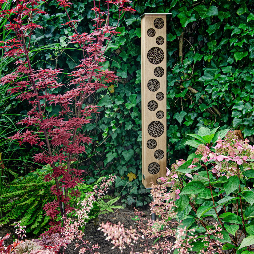 BEE TOWER 80 – puristisches Designobjekt mit charakteristischen runden Ausfräsungen, das mit rund 500 austauschbaren Nisthülsen Lebensraum für unterschiedliche Bienen- und Wespenarten bietet.