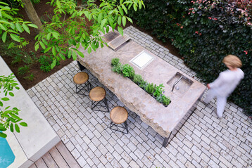 Als skulpturaler Mittelpunkt im Freien verbindet MKA01 von Hauser Naturstein rauen Stein mit pr�zisem Stahl zu einem funktionalen Ort der Begegnung und des kulinarischen Genusses.