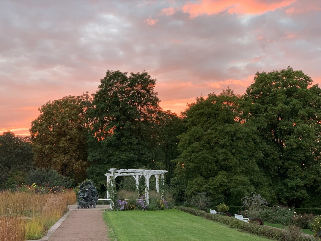 Halbrunde Rosenpergola mit Stauden und Skulptur von Schlotter